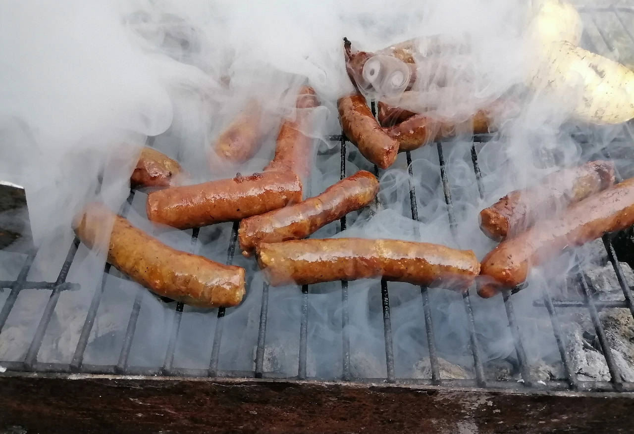 Smoky grilled sausages on barbecue.