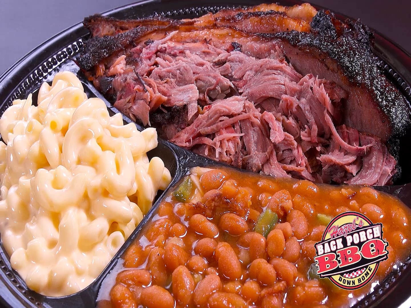 A plate of food with meat, beans and macaroni.