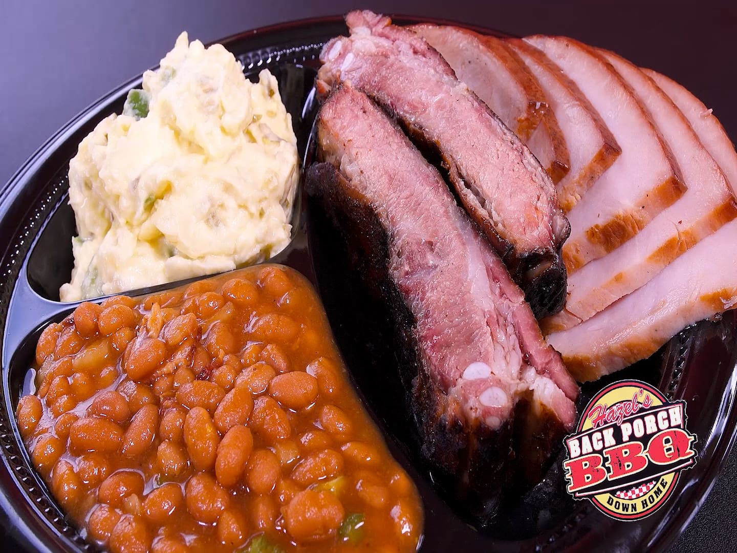 A plate of food with beans, mashed potatoes and meat.
